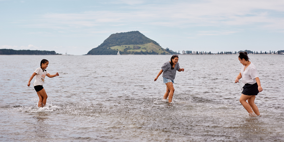 Kids playing in the water with Mount Maunganui in the background